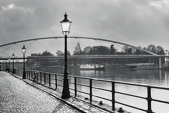 Grau. Ein Bild mit Wasser und Brücke im Hintergrund.